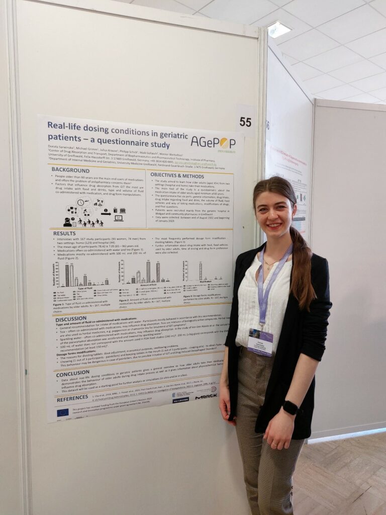 Young lady with conference name tag smiling at the camera next to her research poster.