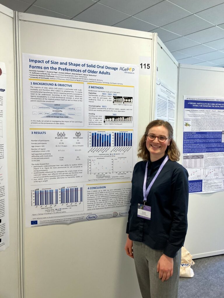 Young lady with conference name tag smiling at the camera next to her research poster.