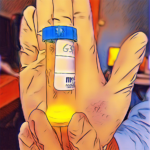 An artistic, digitally enhanced image portrays a hand holding a small, transparent medical vial with a blue cap and a label, possibly containing a yellow substance. The image is given a vivid, glowing outline effect, emphasizing the colors and contours of the hand and the vial in a striking, illustrative manner.